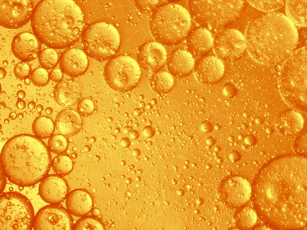Makro: orangefarbene Öltröpfchen und Bläschen in Flüssigkeit