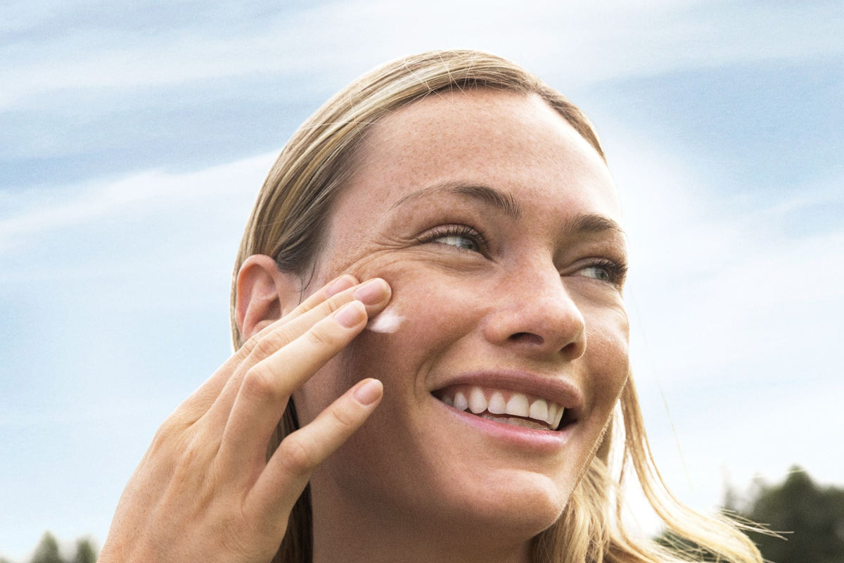 Frau in der Natur trägt die Creme auf das Gesicht auf
