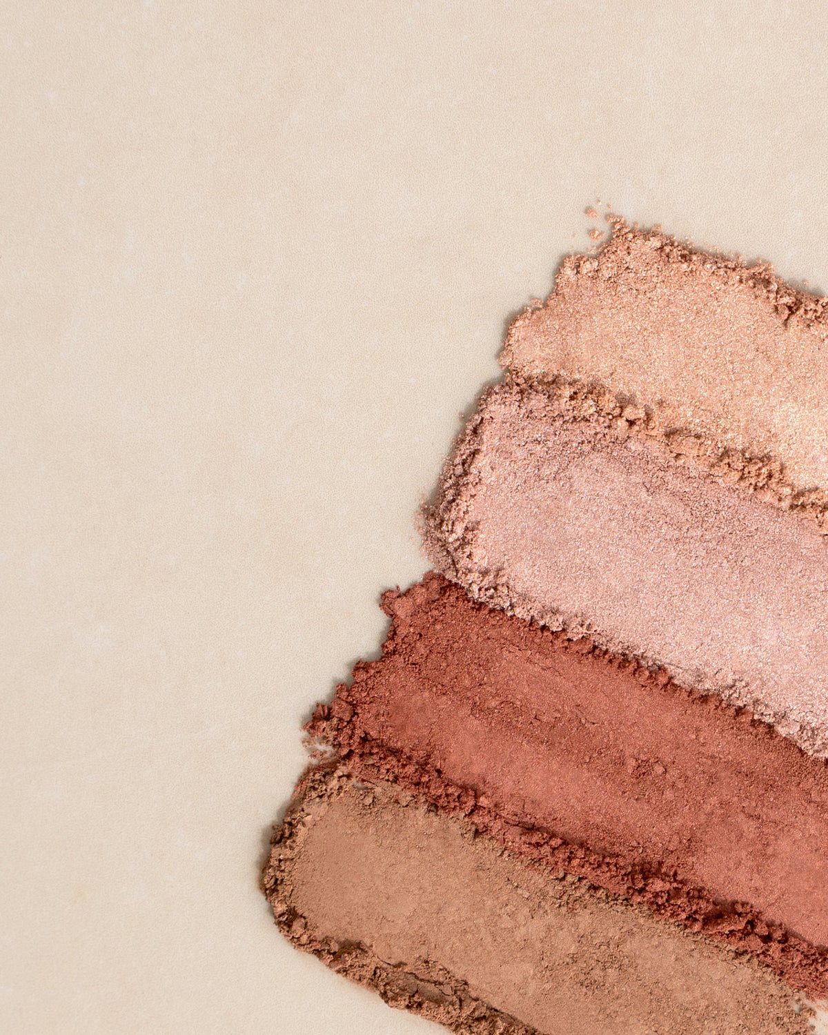 Drei Farb-Swatches von pudrigem Make-up in Nude-, Rosa- und Kupfertönen auf hellem Untergrund