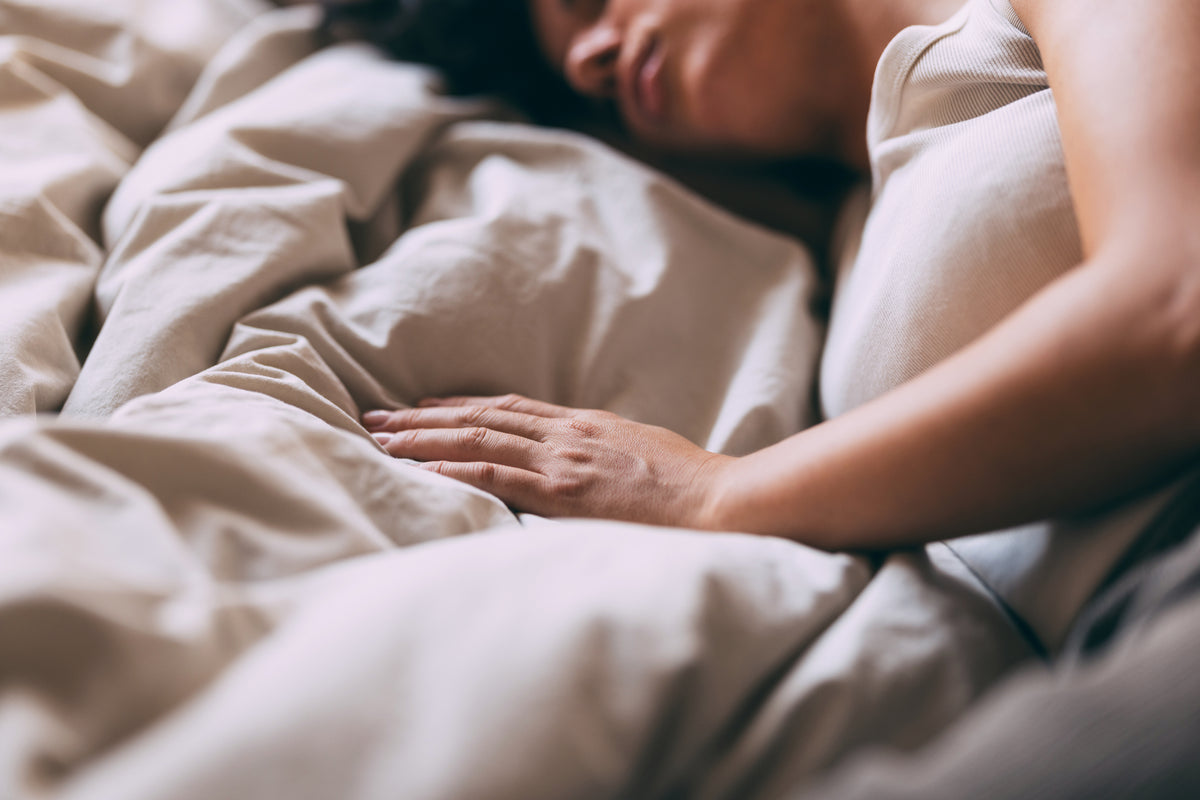 Frau liegt auf einem Bett mit grauem Bettbezug