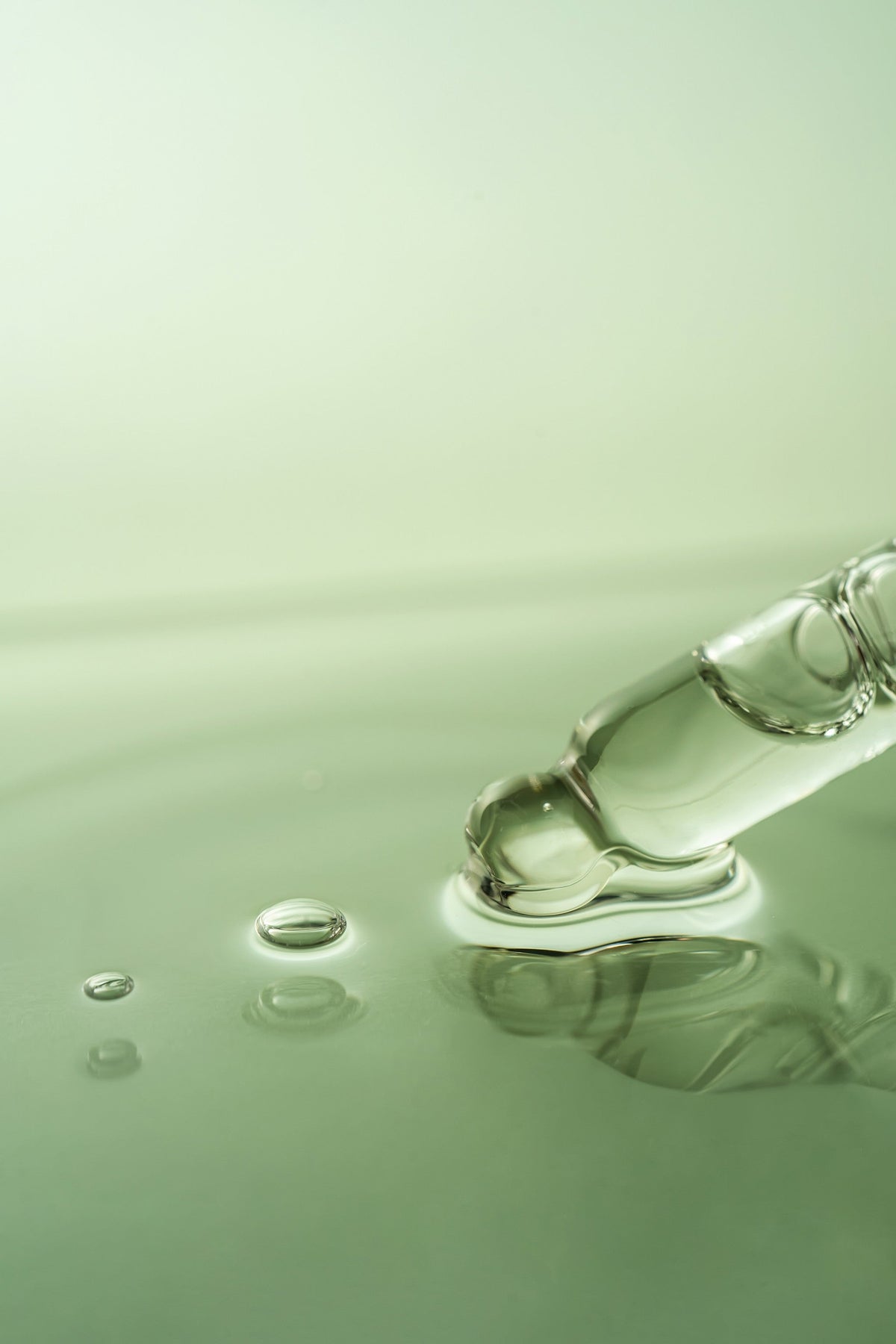 Nahaufnahme einer Pipette mit klarer Flüssigkeit, die Tropfen in Wasser abgibt.