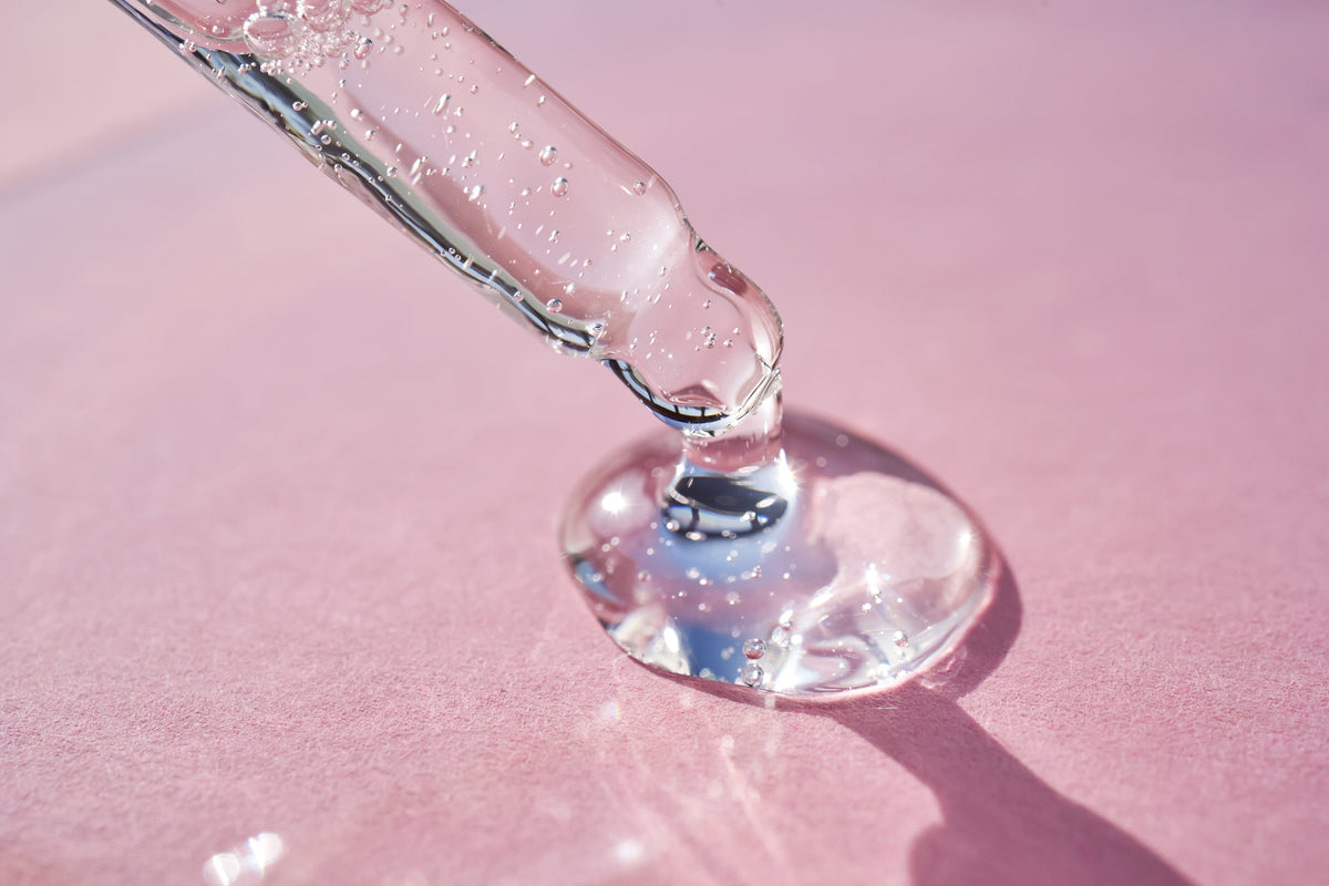 Pipette mit Serum vor einem pinken Hintergrund