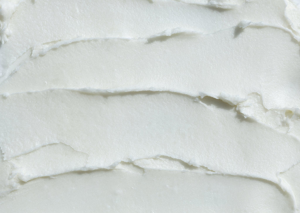Nahaufnahme von cremig-weißer Sheabutter in geschichteten Strukturen.