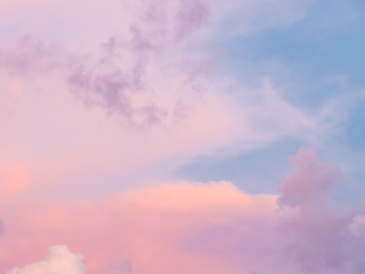 Zart rosa-blauer Himmel mit weichen Wolken bei Sonnenuntergang.
